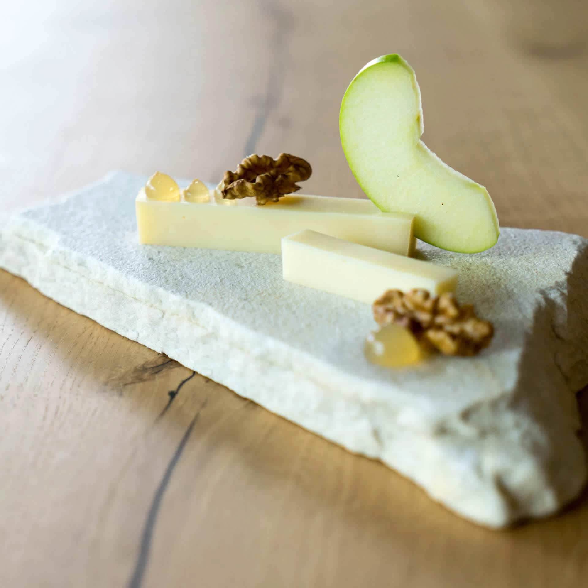 Käseanschnitt mit Birnen und Walnüssen auf Holzbrett angerichtet.