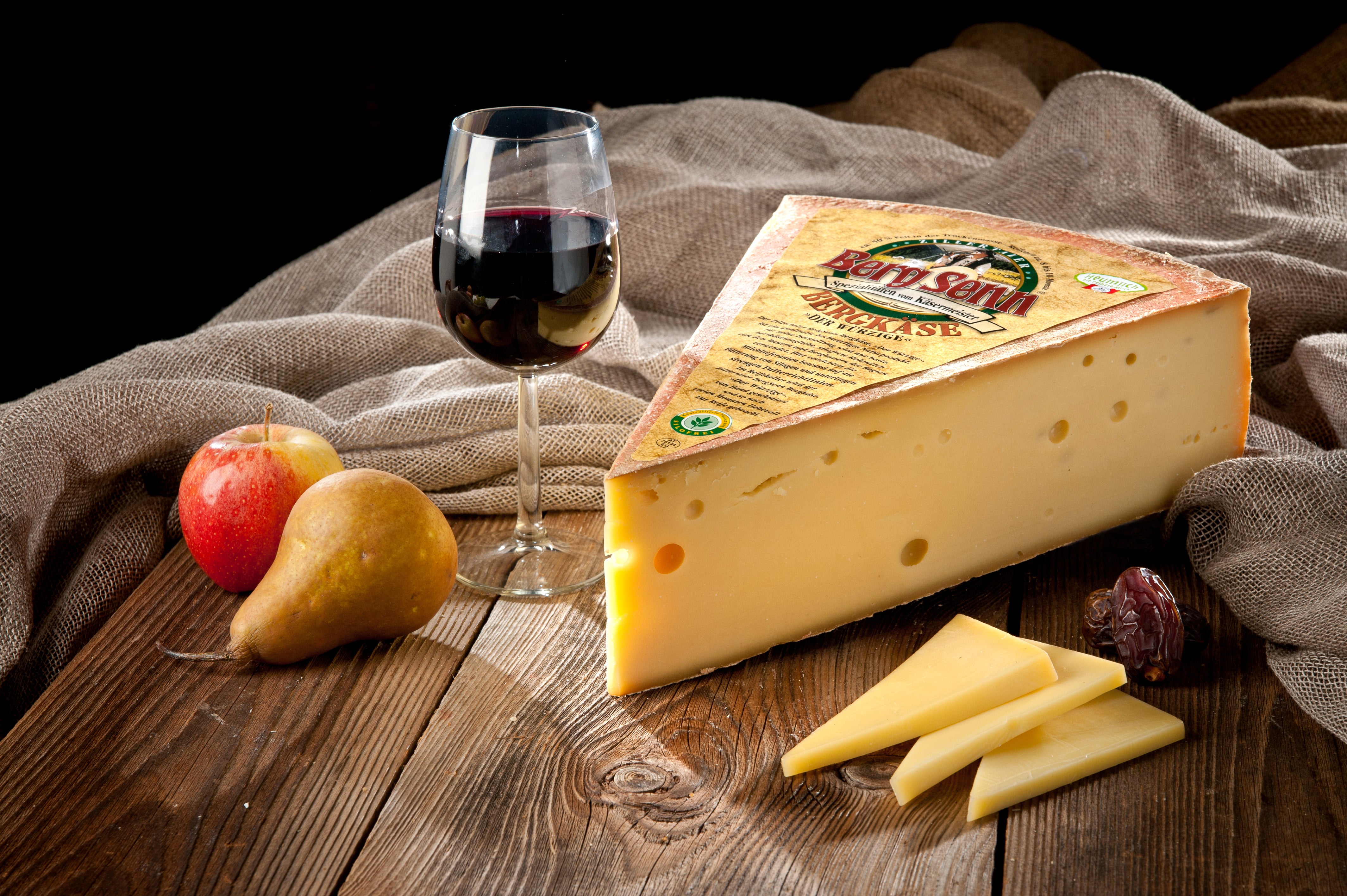 Käsekeil mit Etikett, Rotwein, Apfel und Birne auf Holzbrett