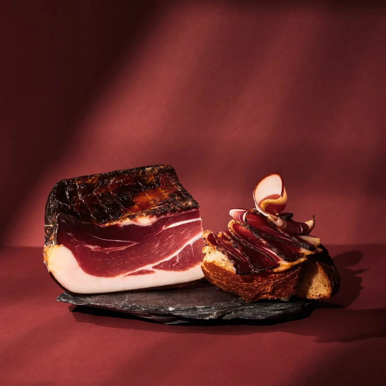 Speck auf Schieferplatte mit Brotkruste